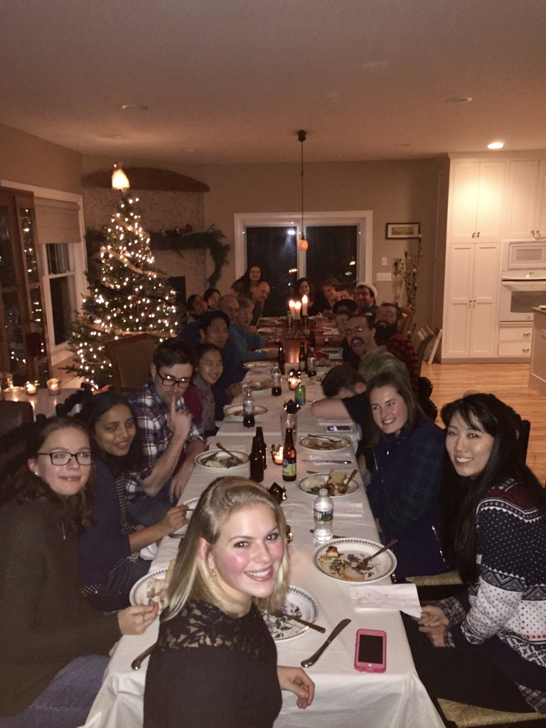 Lab members enjoying dinner at a very long table at the Lab Holiday Party at the Goldhamer’s