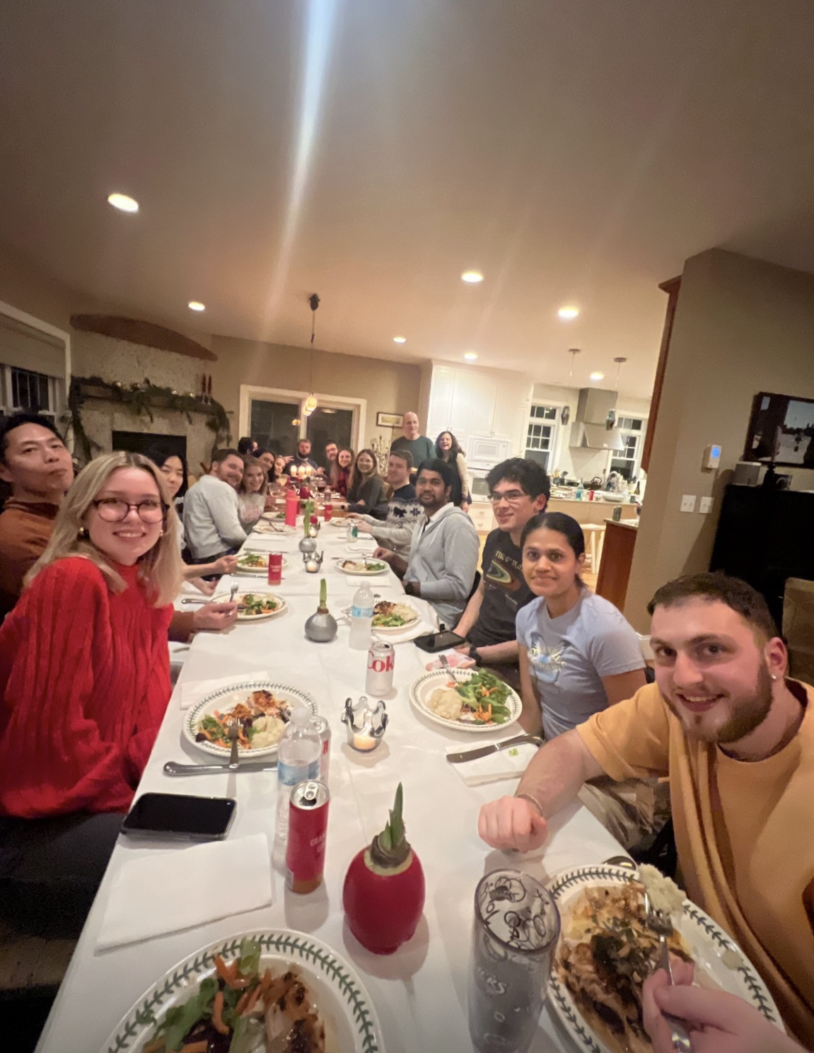 Lab members enjoying dinner at a very long table at the Lab Holiday Party at the Goldhamer’s: